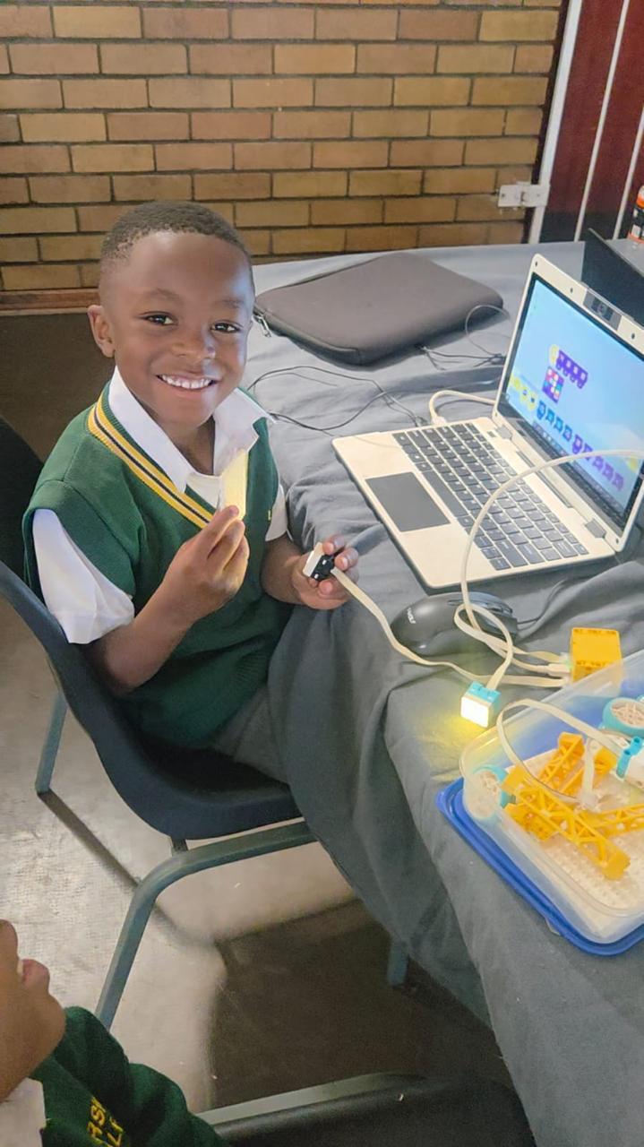Young boy coding on a laptop with a robotics kit beside him