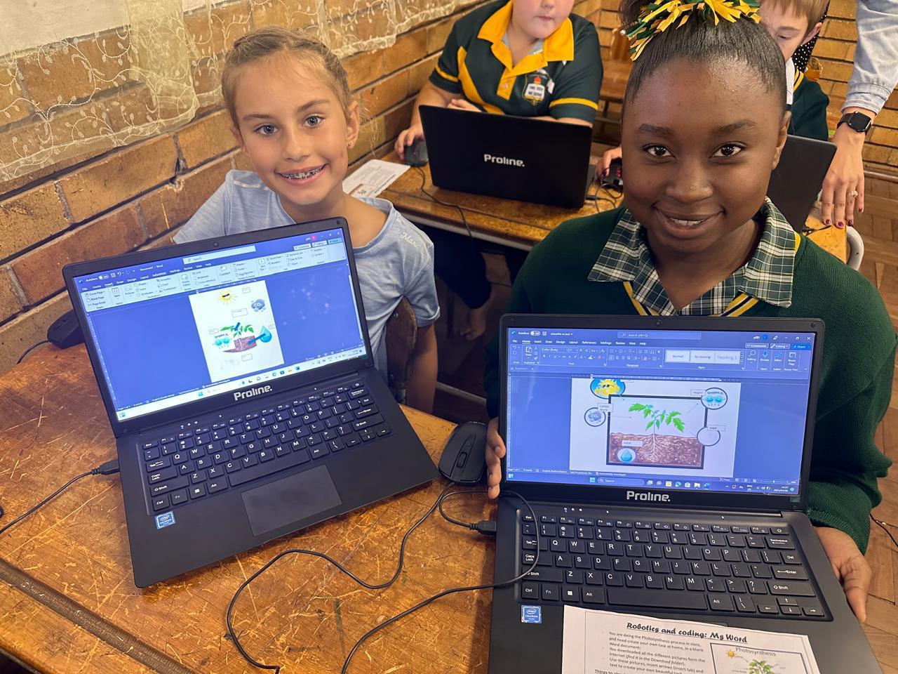 Learners proudly showing their coding and digital design projects on laptops