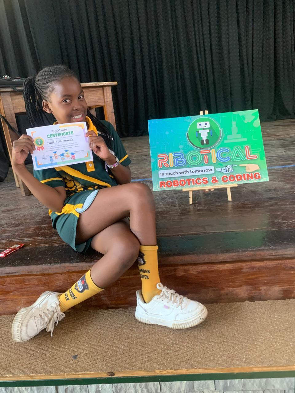 Learner holding a Ribotical certificate of completion next to the branded sign